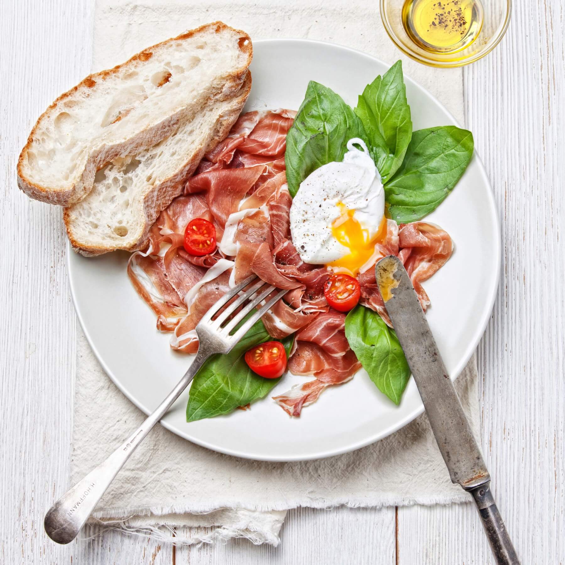 Ham salad with poached egg on white wooden background